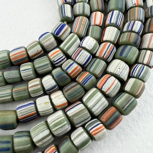 May include: A collection of colorful glass beads with a striped pattern in shades of green, white, blue, and orange. The beads are arranged in a semi-circle, showcasing their unique design.
