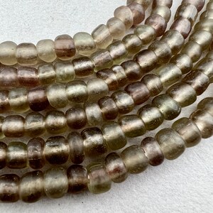 May include: A strand of iridescent green glass beads with a frosted finish. The beads are round and have a slightly irregular shape.