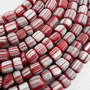 May include: A strand of red and white striped beads. The beads are made of a smooth, polished stone and have a slightly rounded shape.
