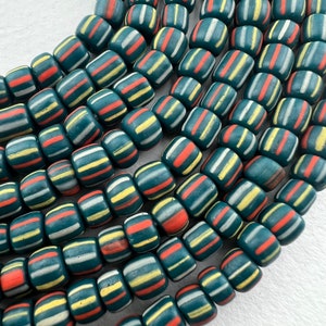 May include: A strand of teal blue and white striped glass beads with a red accent. The beads are round and have a matte finish.