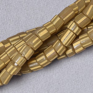 May include: A close-up of a strand of brown and cream coloured glass beads. The beads are cylindrical and have a striped pattern.