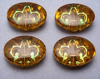May include: Four oval-shaped glass buttons with a gold and green fleur-de-lis design.