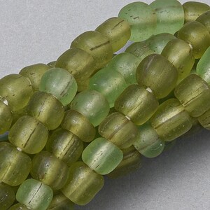 May include: A strand of green glass beads with a frosted finish. The beads are round and have a slightly irregular shape.