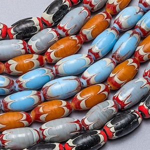 May include: A close-up of a strand of colorful glass beads. The beads are oval-shaped and have a swirling pattern of red, white, blue, and orange. The beads are arranged in a curved line.