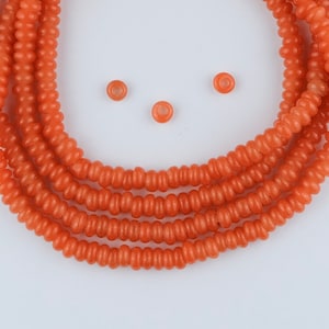 May include: A strand of orange glass beads, with a few loose beads scattered around it.