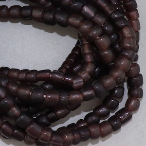 May include: A strand of dark purple glass beads, each bead is square shaped with rounded edges.