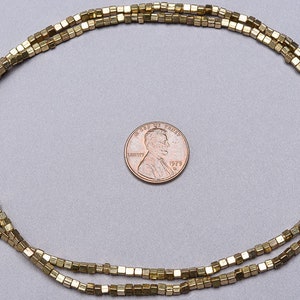 May include: A strand of gold-toned square beads, approximately the size of a US penny.