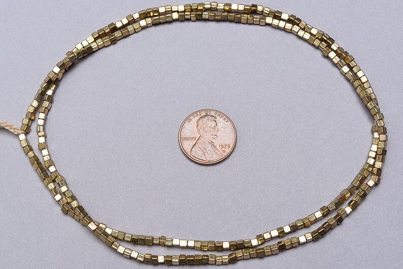 May include: A strand of gold-toned square beads, approximately the size of a US penny.