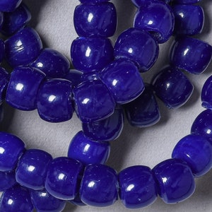 May include: A close-up of a string of dark blue round beads. The beads are smooth and shiny, and they are arranged in a random pattern.