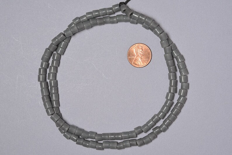 May include: A strand of gray ceramic beads, approximately the size of a US penny.