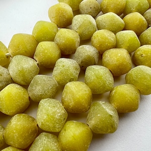 May include: A string of green glass beads with a frosted finish. The beads are faceted and have a slightly irregular shape.