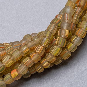 May include: A close-up of a strand of multi-colored glass beads. The beads are translucent and have a striped pattern. The beads are arranged in a circular pattern.
