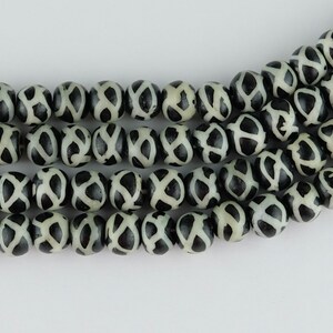 May include: A strand of black and white agate beads with a geometric pattern. The beads are round and have a smooth, polished finish.