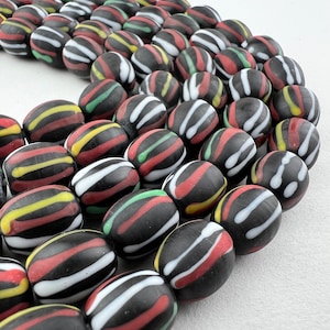 May include: A strand of black, white, red, and yellow striped glass beads. The beads are round and have a glossy finish.
