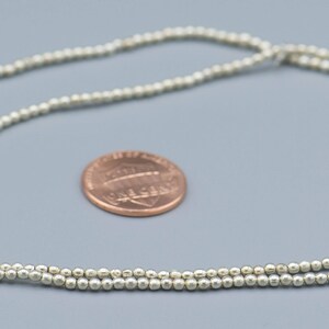 以下が含まれることがあります： 小さな丸いビーズで作られたシルバーネックレス。ネックレスは日本の1円玉と同じくらいの大きさです。