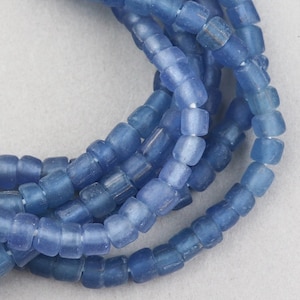 May include: A strand of light blue glass beads. The beads are square shaped and have a frosted finish.