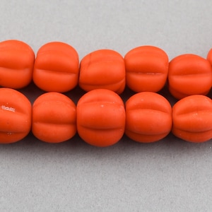 May include: A strand of bright orange glass beads with a slightly rounded, pumpkin-like shape.
