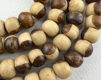 May include: A strand of brown and beige wooden beads with a mottled pattern. The beads are round and have a smooth, polished finish.