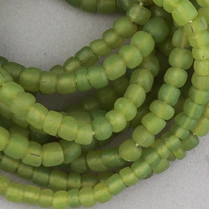 May include: A strand of green glass seed beads. The beads are small and round, and they have a slightly frosted finish.
