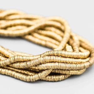 May include: A strand of gold-colored metal beads, each bead is a flat, round disc with a slightly textured surface.