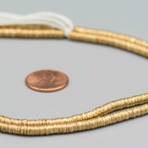 Pu&ograve; includere: Una collana di perline di metallo dorato, circa della dimensione di una moneta da un centesimo di euro.