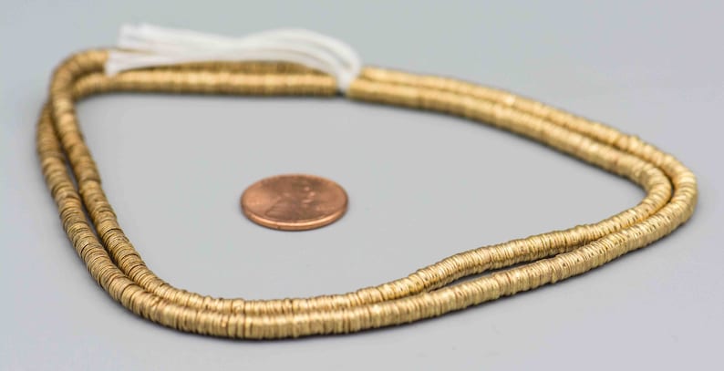 Pu&ograve; includere: Una collana di perline di metallo dorato, circa della dimensione di una moneta da un centesimo di euro.