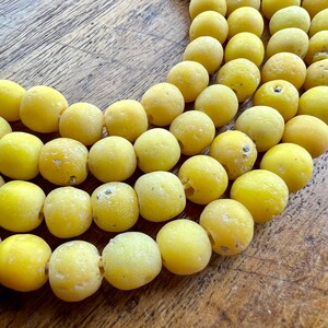 May include: A strand of yellow glass beads, each bead is round and has a textured surface.