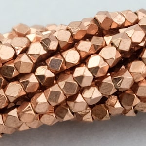 Peut inclure: Un brin de perles facettées de couleur cuivre. Les perles sont petites et ont un éclat métallique.