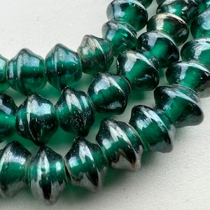 May include: A strand of dark green glass beads with a silver iridescent finish. The beads are faceted and have a slightly irregular shape.