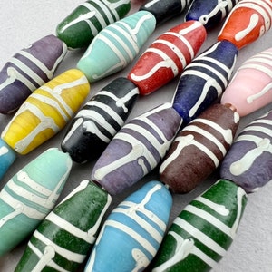 May include: A collection of colorful glass beads with white stripes. The beads are oval shaped and have a glossy finish.