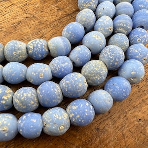 Peut inclure: Un brin de perles de verre bleu clair avec une finition blanche mouchetée. Les perles sont de forme ovale et ont une surface rugueuse et texturée.