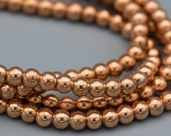 May include: Close-up of a strand of copper-colored beads. The beads are round and have a shiny, metallic finish.