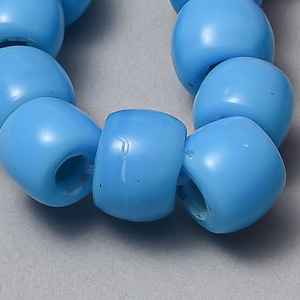 May include: Close-up of a strand of light blue beads. The beads are smooth, rounded, and have a hole running through the center. The beads are strung together, creating a curved shape.