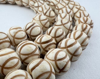 May include: A strand of white and brown patterned beads. The beads are round and have a carved design.