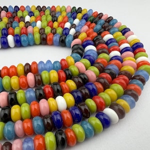 May include: A strand of colourful glass beads, featuring a variety of colours and shapes. The beads are arranged in a circular pattern, creating a visually appealing display.