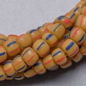 May include: A strand of yellow glass beads with red and blue stripes. The beads are round and have a matte finish.