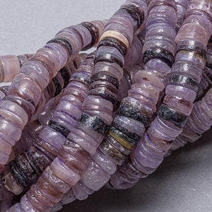 May include: A strand of purple and white shell beads. The beads are flat and round, and they have a natural, organic look.