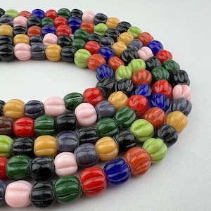 May include: A strand of colorful glass beads, featuring a variety of colors and shapes. The beads are arranged in a circular pattern, creating a visually appealing and textured design.
