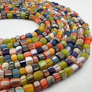 May include: A collection of colorful, striped glass beads. The beads are arranged in a circle, with the ends of the strands overlapping. The beads are all different colors, including red, orange, yellow, green, blue, and purple.