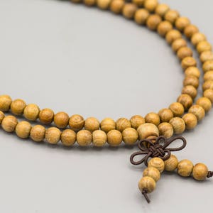 May include: A brown wooden beaded necklace with a knotted tassel. The beads are round and have a natural wood grain.