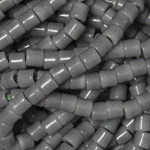 May include: A pile of gray, round, ceramic beads with a speckled texture. The beads are approximately 1/2 inch in diameter.