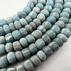 Peut inclure: Un brin de perles en verre bleu et blanc avec une surface marbrée et texturée. Les perles sont rondes et ont une forme légèrement irrégulière.