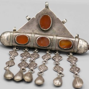May include: A silver pendant with a triangular top and a rectangular body. The pendant is decorated with five carnelian stones and has a chain of silver charms hanging from the bottom.