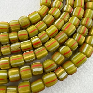 May include: A strand of green glass beads with white and red stripes. The beads are cylindrical and have a glossy finish.