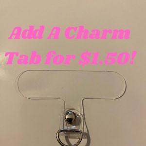 May include: A clear plastic charm tab with a silver-colored metal ring and a silver-colored metal stud. The text "Add A Charm Tab for $1.50!" is in pink, stylized font.
