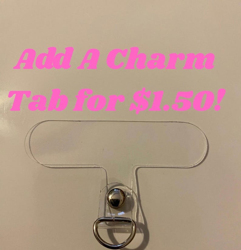 May include: A clear plastic charm tab with a silver-colored metal ring and a silver-colored metal stud. The text "Add A Charm Tab for $1.50!" is in pink, stylized font.