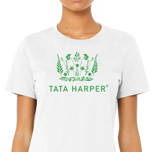 May include: White t-shirt with a green floral design and the text "TATA HARPER". The design features various leaves and flowers. The shirt is a crew neck and short-sleeved.