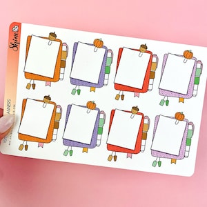 Puede incluir: Hoja de pegatinas para planificador con blocs de notas coloridos con forma de suéter. Cada bloc de notas tiene un papel blanco en blanco, un clip decorativo y un marcador. Las pegatinas están decoradas con bellotas y calabazas, en tonos de naranja, rojo, morado y verde.