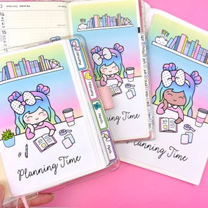 May include: A colorful planner with a rainbow gradient background. The planner has a monthly calendar, a weekly calendar, and a section for planning time. The planner is decorated with cute illustrations of girls with bows and books. The planner has tabs for each month of the year.