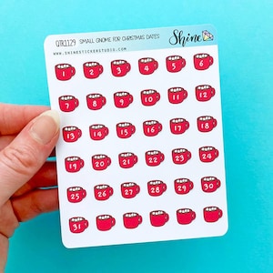 May include: A sheet of stickers featuring red mugs with white marshmallows and numbers 1-31. The text "QTR1129 SMALL GNOME FOR CHRISTMAS DATES" and "www.shinestickerstudio.com" are printed on the sticker sheet.